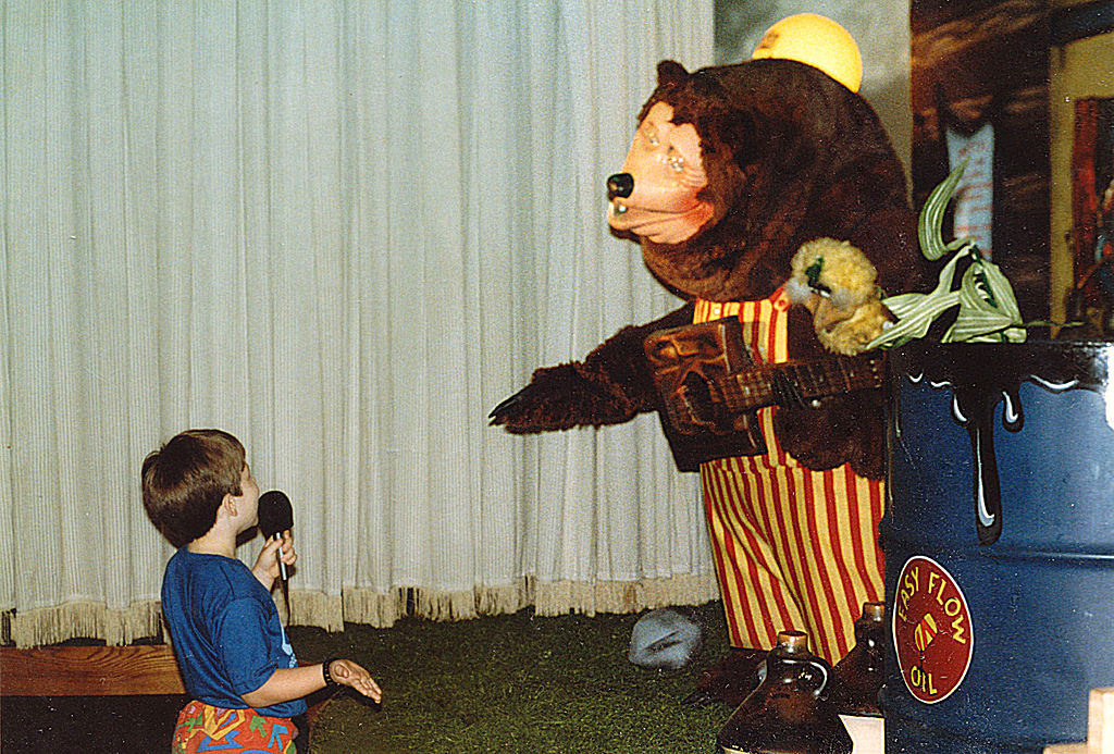 A child uses a microphone to speak to Billy Bob, mascot of ShowBiz Pizza Place, during a birthday party at ShowBiz Pizza in Fayetteville, Arkansas