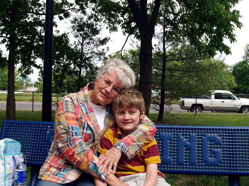 Smiling grandson and grandmother on park bench