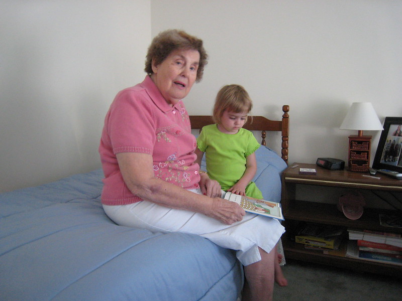 Grandma reading to her granddaughter on the bed