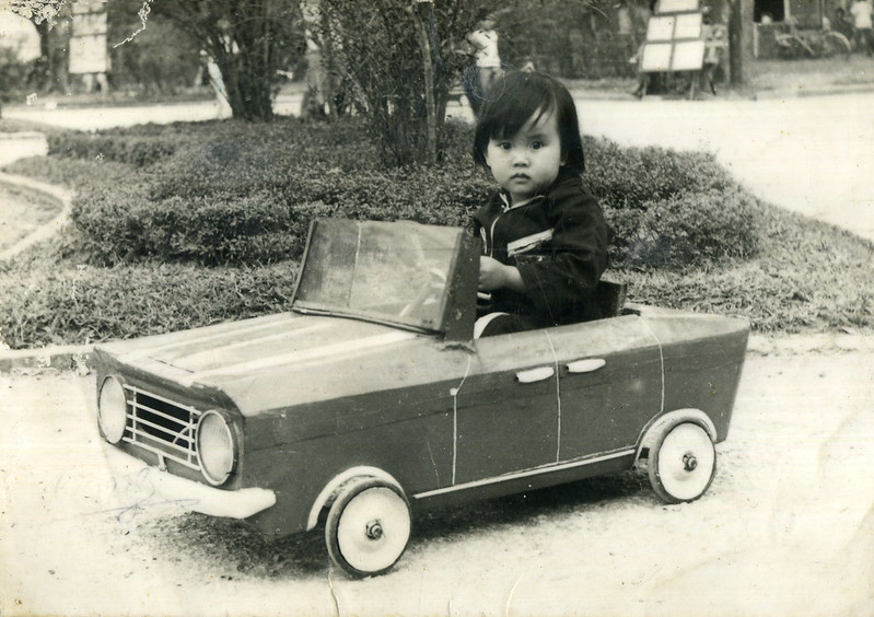 Old photo of a little kid in a toy vehicle