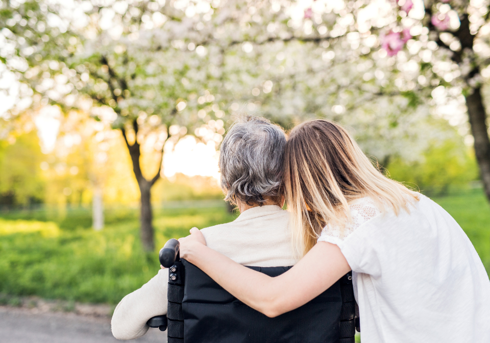 A girl outside with Grandma in a wheelchair enjoying the view