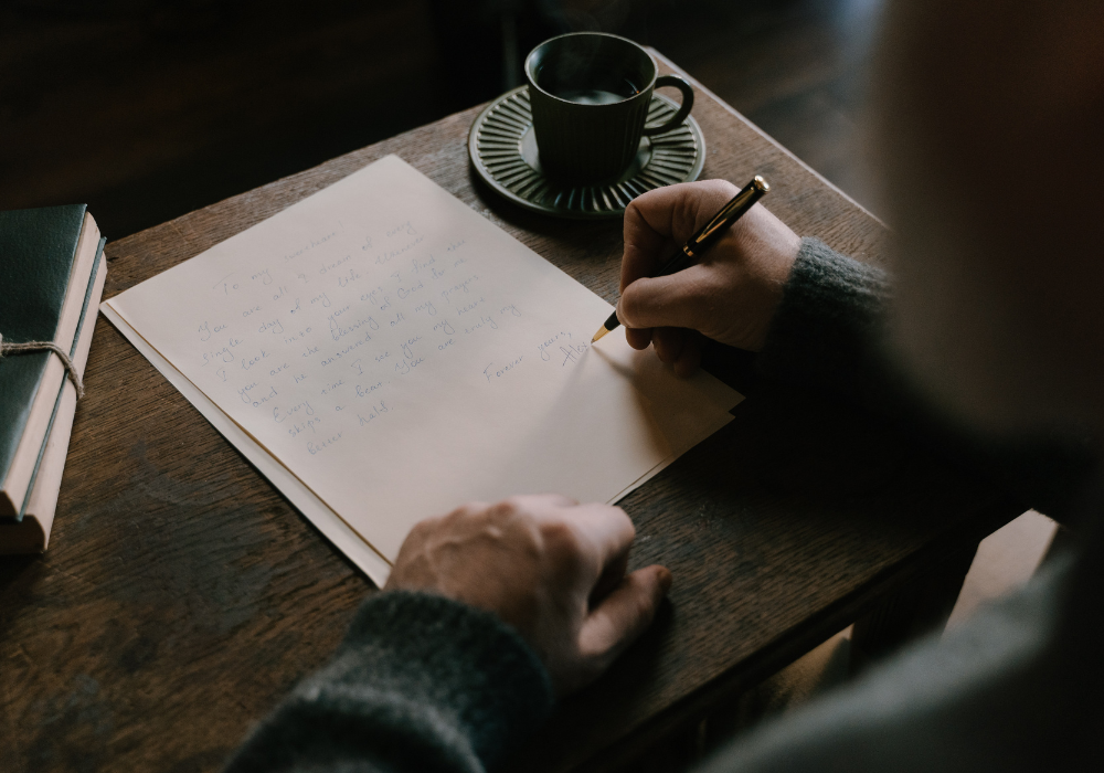 Writing a letter at a table with a cup of coffee